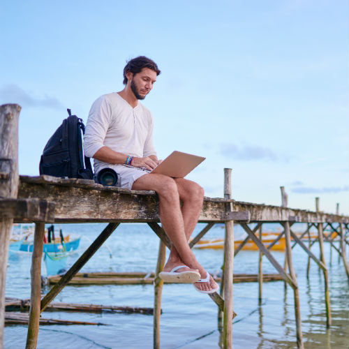 Fellow working on a laptop by the ocean