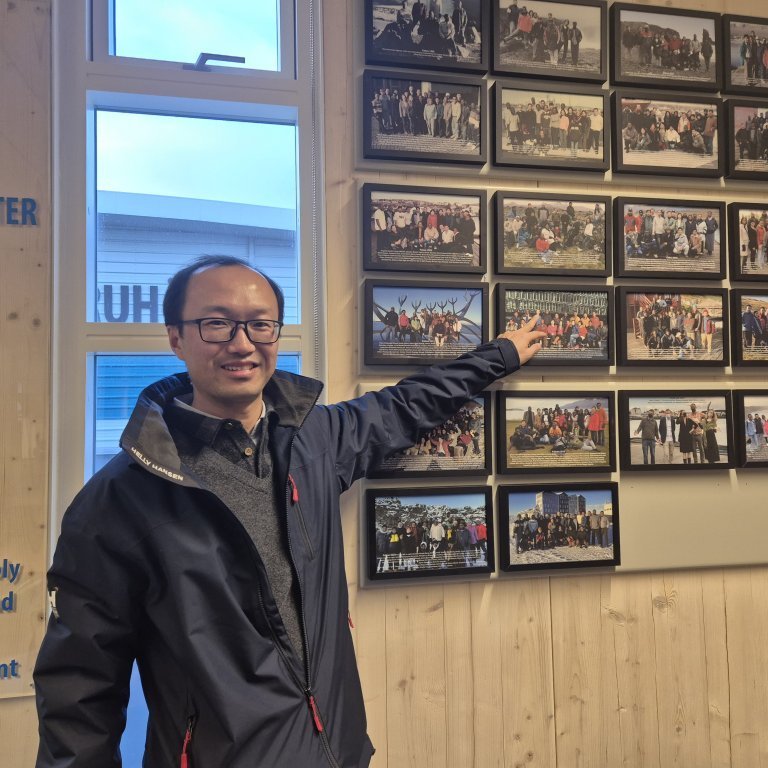 Xing Kun a fellow from 2014 pointing at a group photo of his cohort